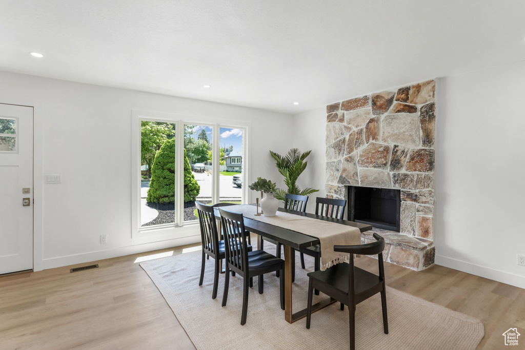 Dining space featuring baseboards, light wood finished floors, a fireplace, and recessed lighting