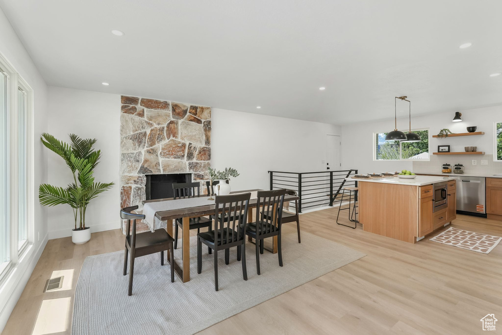 Dining room with light wood-style flooring, recessed lighting, and a fireplace