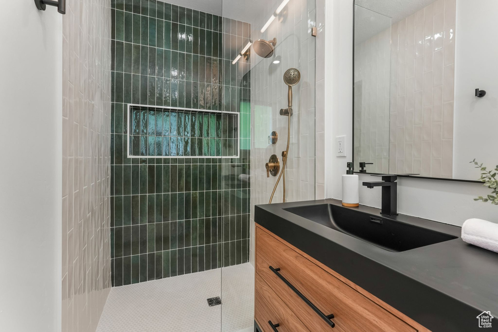 Bathroom featuring tiled shower and vanity