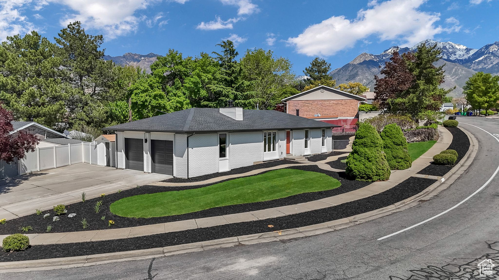 Ranch-style home featuring a mountain view, a garage, fence, and brick siding