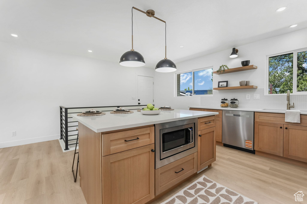 Kitchen featuring appliances with stainless steel finishes, a sink, light wood-style flooring, backsplash, and recessed lighting