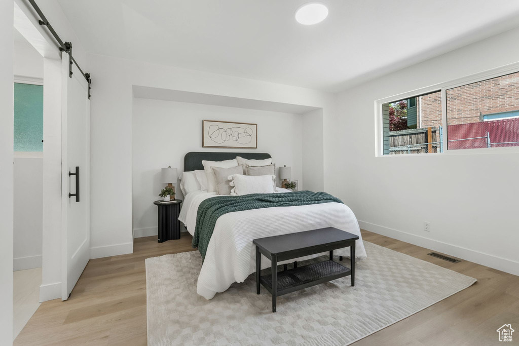 Bedroom featuring a barn door, light wood finished floors, and baseboards