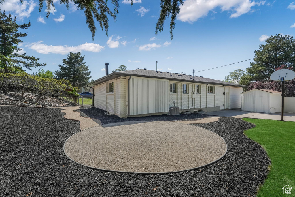 Rear view of house with a patio, fence, brick siding, an outdoor structure, and cooling unit