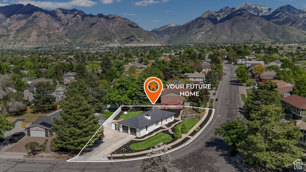 Aerial view of residential area featuring property boundaries highlighted and a mountainous background