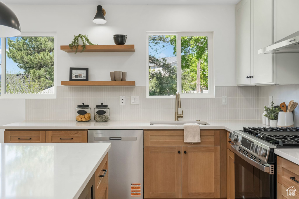 Kitchen with stainless steel appliances, a sink, light countertops, and tasteful backsplash