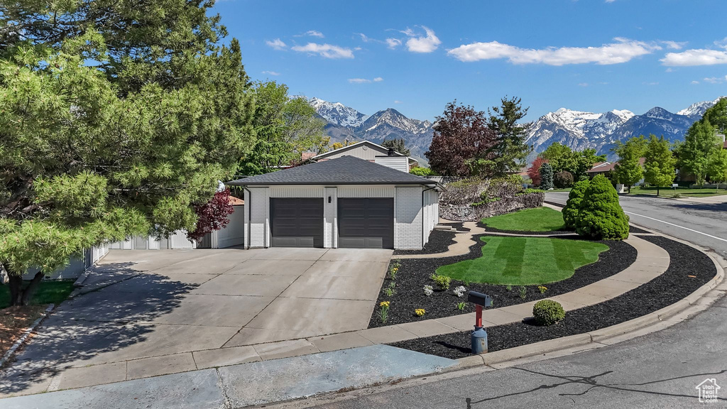 View of front of property with a mountain view, driveway, an attached garage, and brick siding