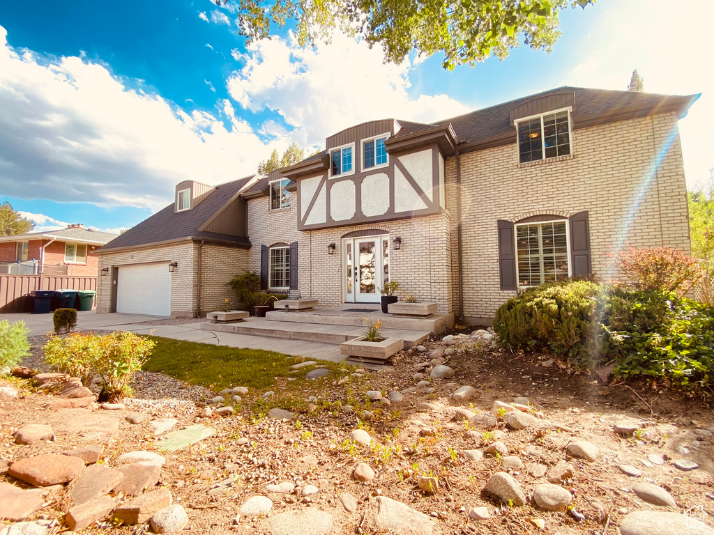 Tudor-style house featuring brick siding, an attached garage, and driveway