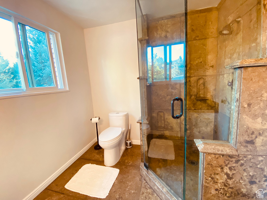 Full bathroom featuring a stall shower, toilet, and baseboards