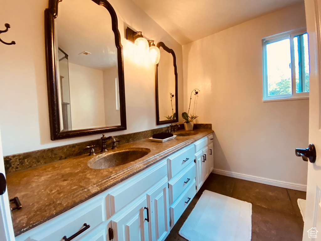 Full bathroom with double vanity and baseboards