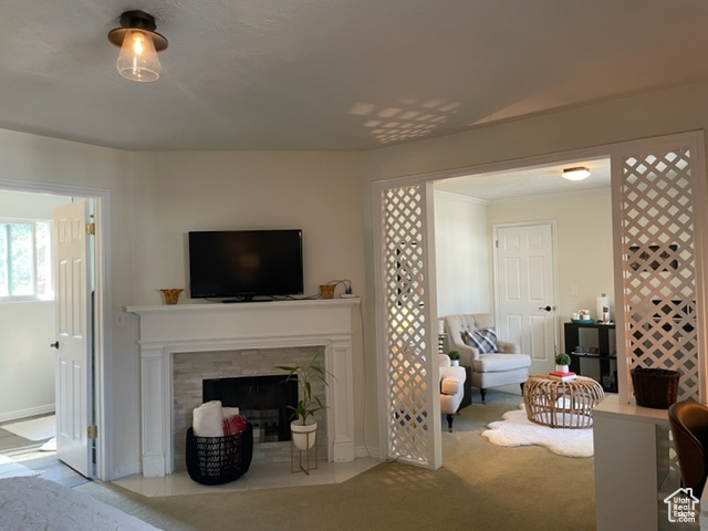 Carpeted living room featuring a tile fireplace and baseboards