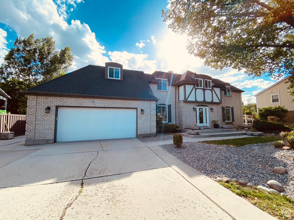 View of front of property with brick siding, concrete driveway, and an attached garage