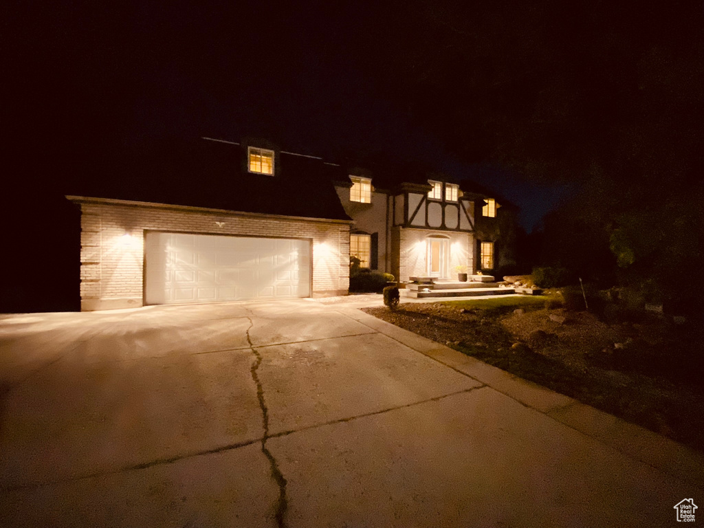 View of front facade with driveway, a garage, and brick siding