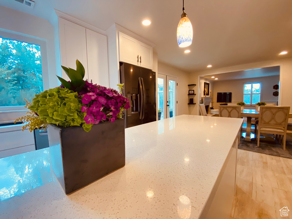 Kitchen featuring refrigerator with ice dispenser, recessed lighting, white cabinets, light stone countertops, and light wood-style flooring