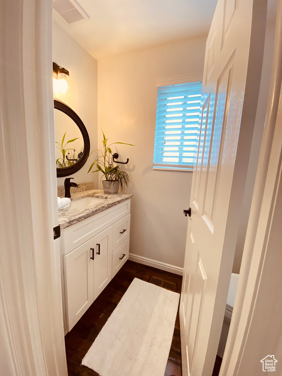 Bathroom featuring vanity, wood finished floors, and baseboards