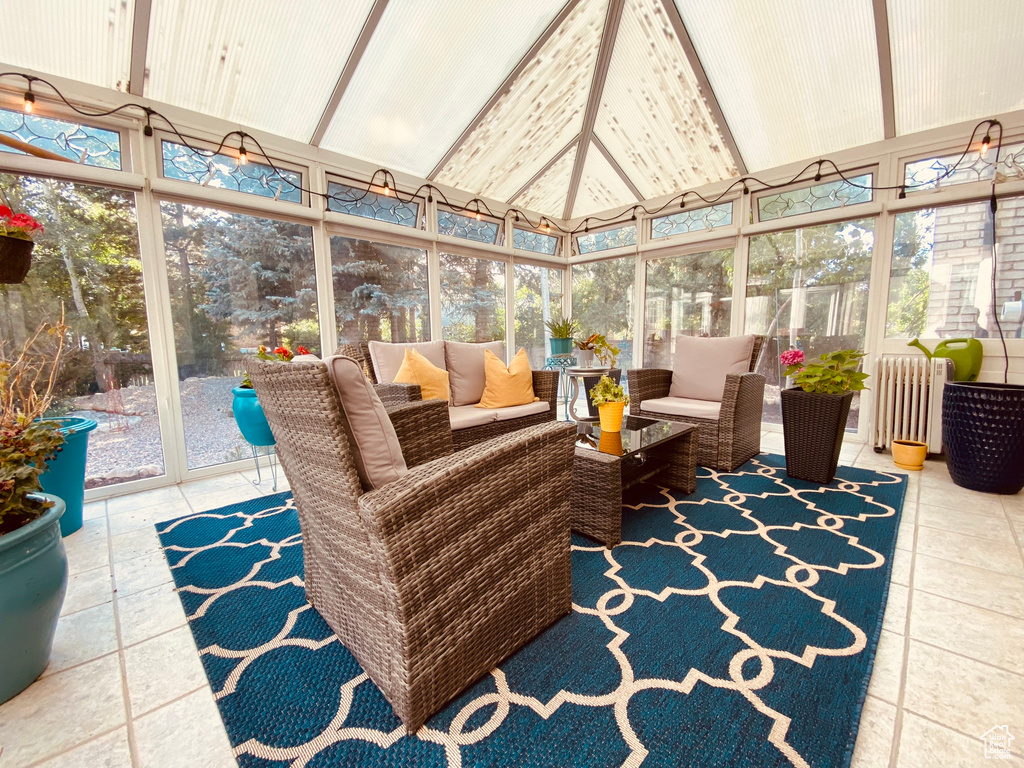 Sunroom featuring outdoor lounge area, healthy amount of natural light, vaulted ceiling, and radiator heating unit