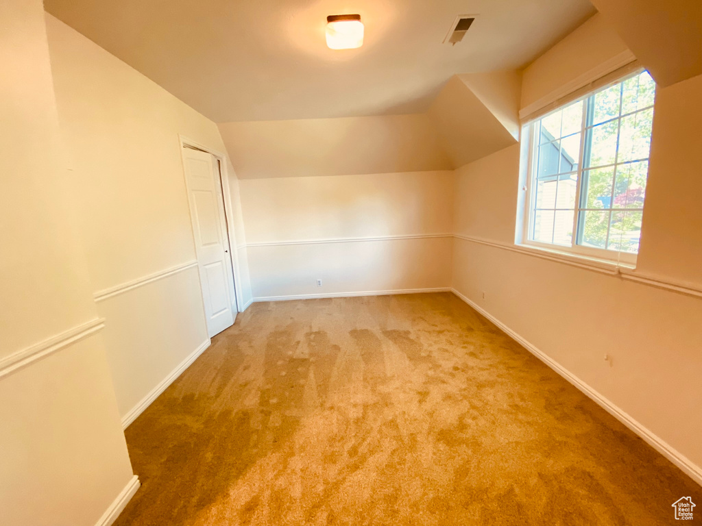 Bonus room featuring lofted ceiling, carpet, and baseboards