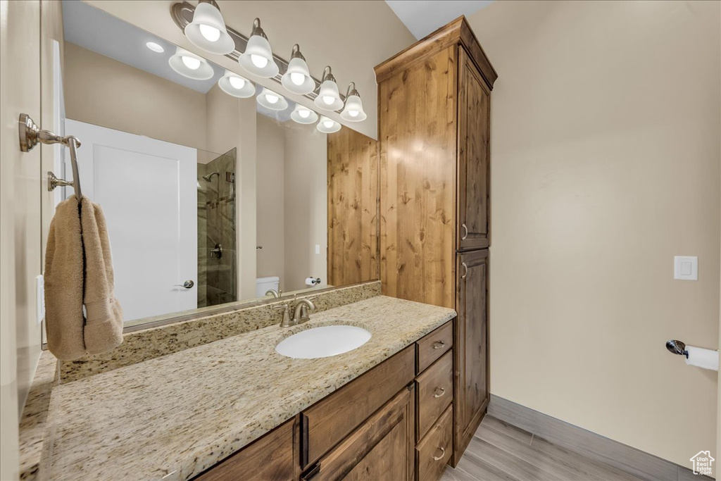Full bathroom with toilet, a shower, vanity, baseboards, and wood finished floors