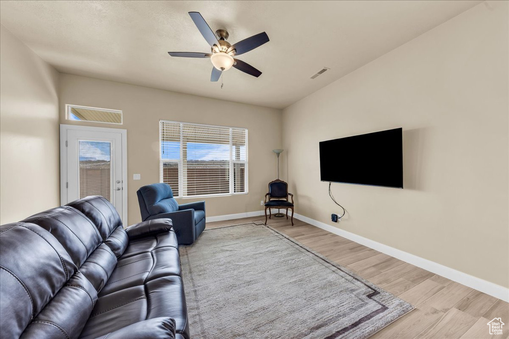 Living area with wood finished floors, a ceiling fan, and baseboards