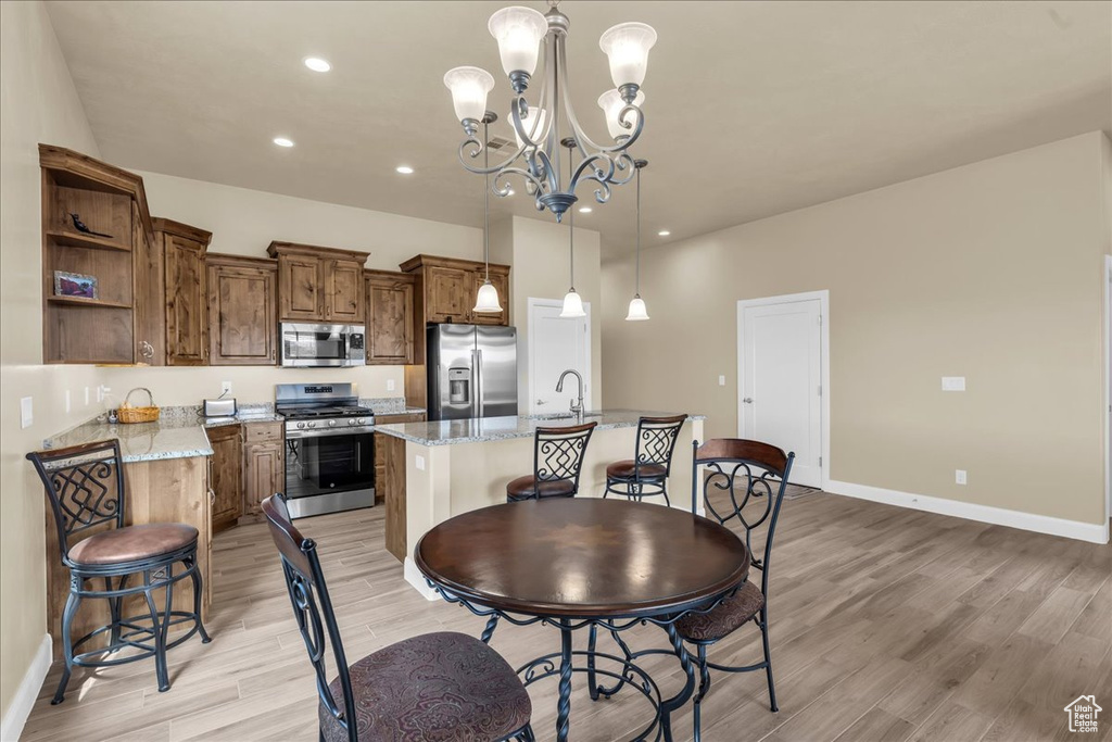 Dining space with light wood finished floors, baseboards, a chandelier, and recessed lighting