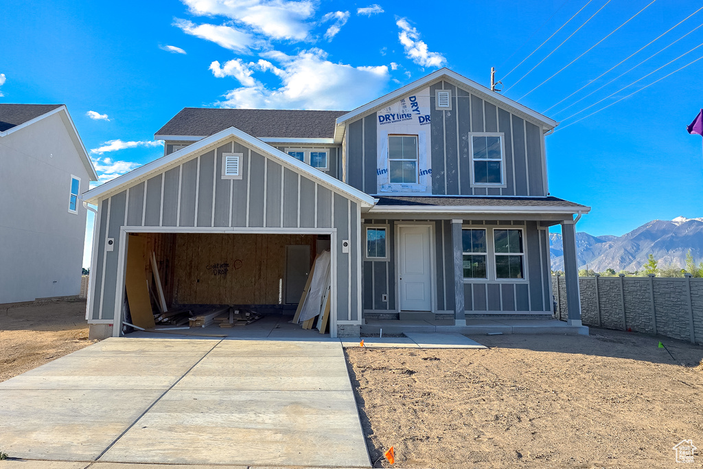 View of front of home featuring driveway, board and batten siding, an attached garage, fence, and a mountain view