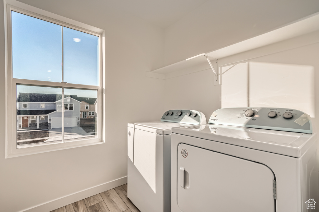 Laundry room with washer and dryer, light wood-type flooring, and baseboards