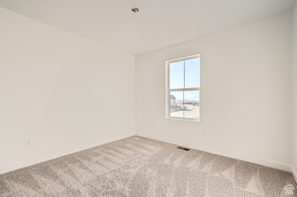 Carpeted spare room featuring baseboards