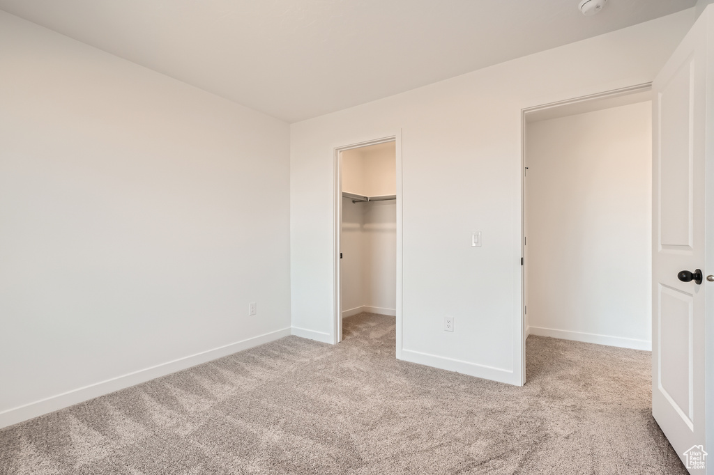 Unfurnished bedroom with carpet floors, baseboards, a spacious closet, and a closet