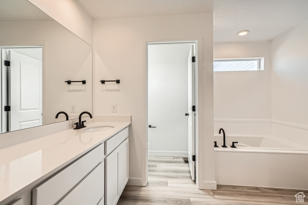 Bathroom with vanity, wood finished floors, a bath, and recessed lighting