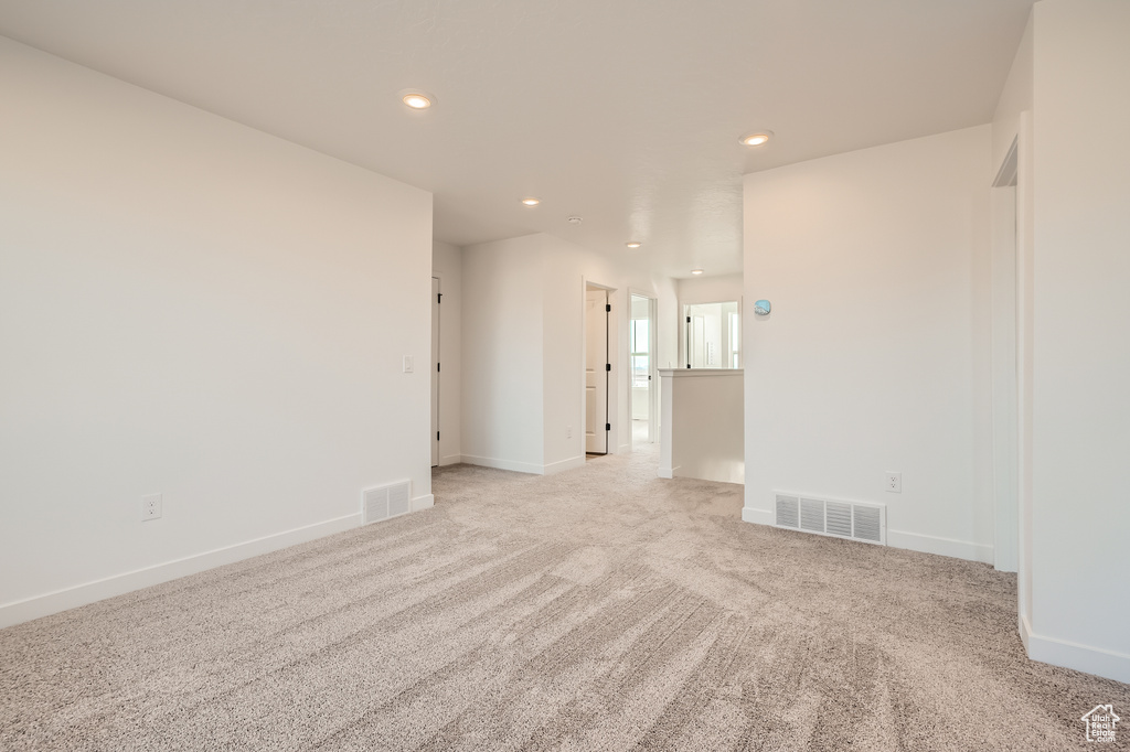 Spare room featuring recessed lighting, light colored carpet, and baseboards