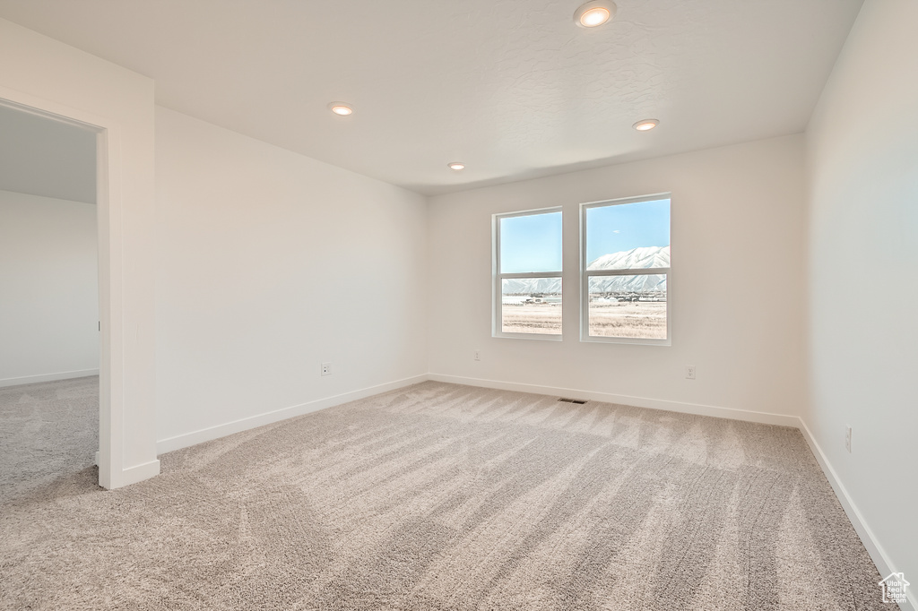 Spare room featuring light colored carpet, recessed lighting, and baseboards