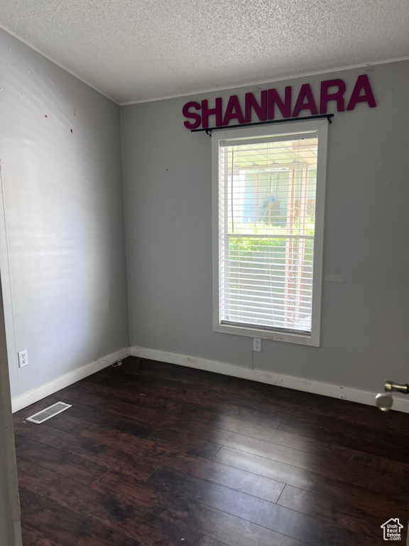 Empty room featuring a textured ceiling, wood finished floors, and baseboards