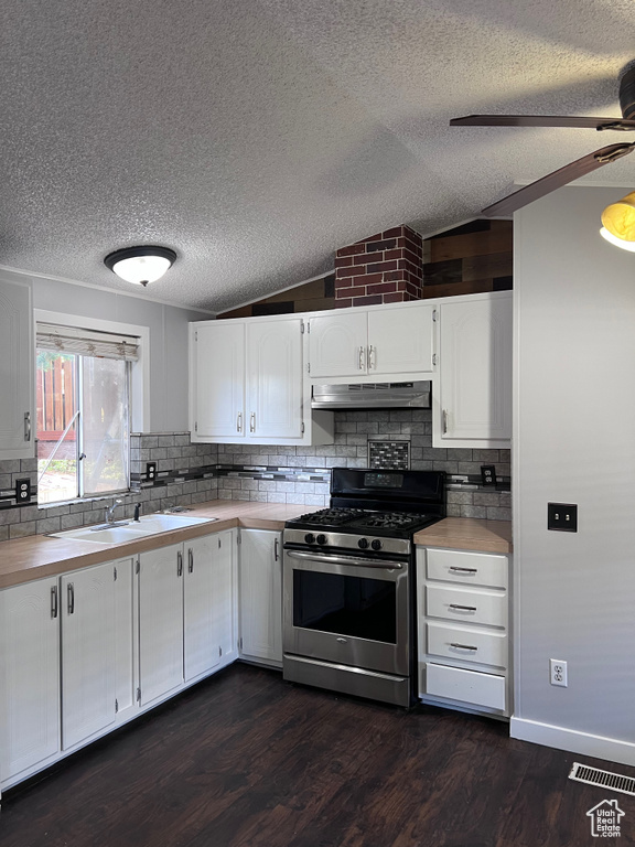 Kitchen featuring stainless steel range with gas cooktop, under cabinet range hood, a textured ceiling, a sink, and vaulted ceiling