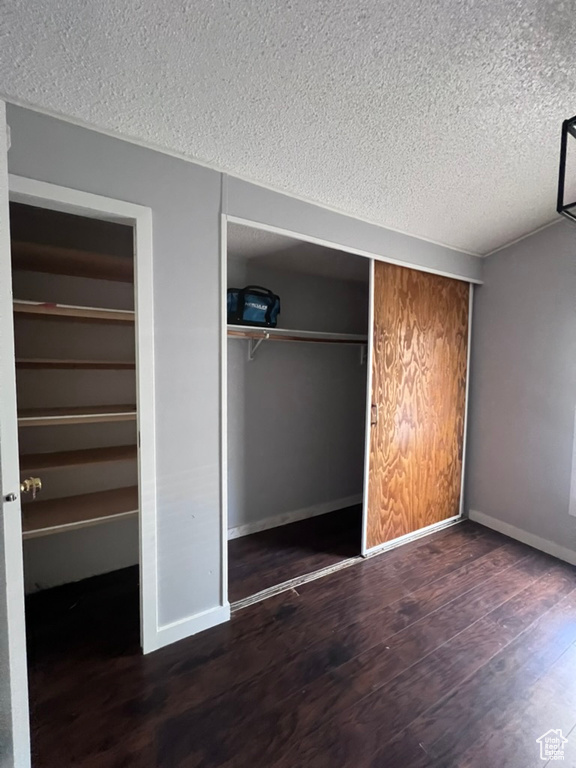 Unfurnished bedroom with a textured ceiling, wood finished floors, and baseboards
