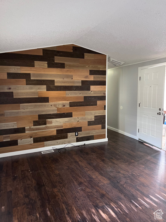 Detailed view of wood walls, wood finished floors, a textured ceiling, and baseboards