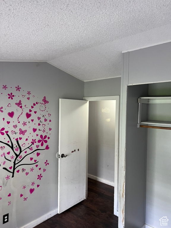 Unfurnished bedroom with wood finished floors, a textured ceiling, a closet, and lofted ceiling