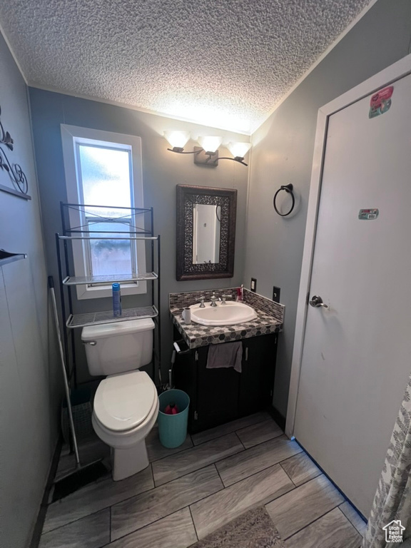 Bathroom with a textured ceiling, vanity, and toilet