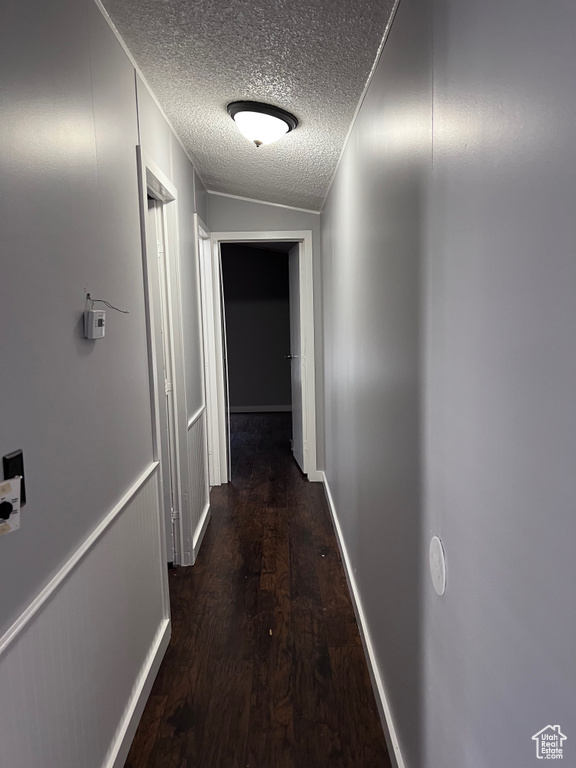 Hall featuring wood-type flooring, a textured ceiling, and baseboards