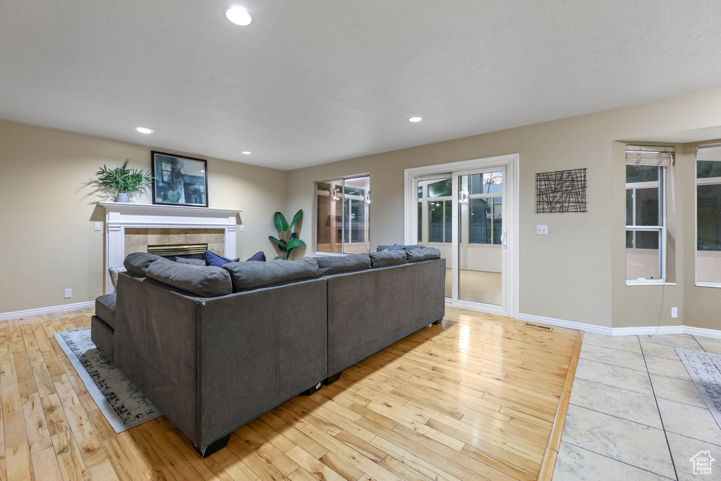 Living room featuring light wood-style flooring, baseboards, a tile fireplace, and recessed lighting