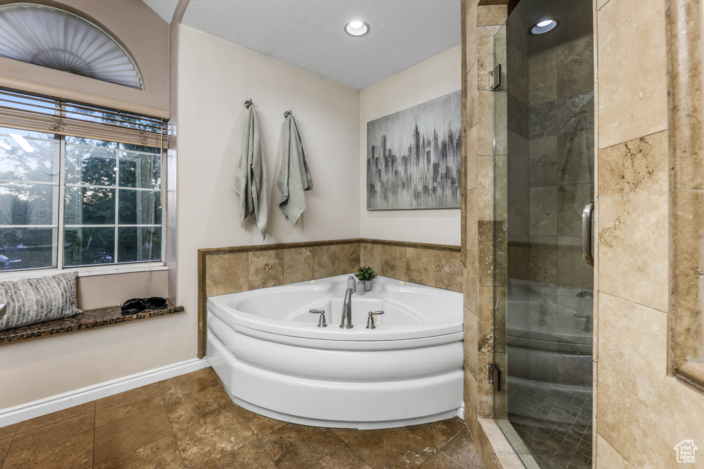 Bathroom featuring a shower stall, a garden tub, baseboards, recessed lighting, and a textured ceiling