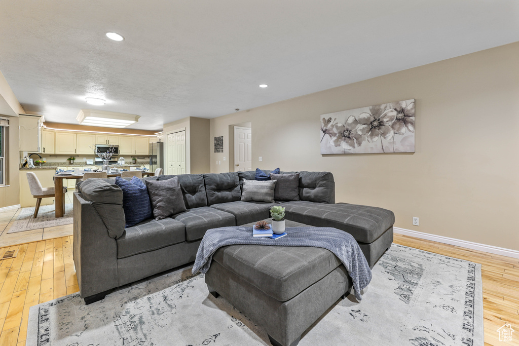 Living area featuring light wood-type flooring, baseboards, and recessed lighting