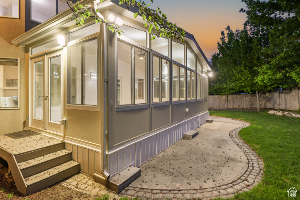 View of property exterior with a sunroom, french doors, and a patio area