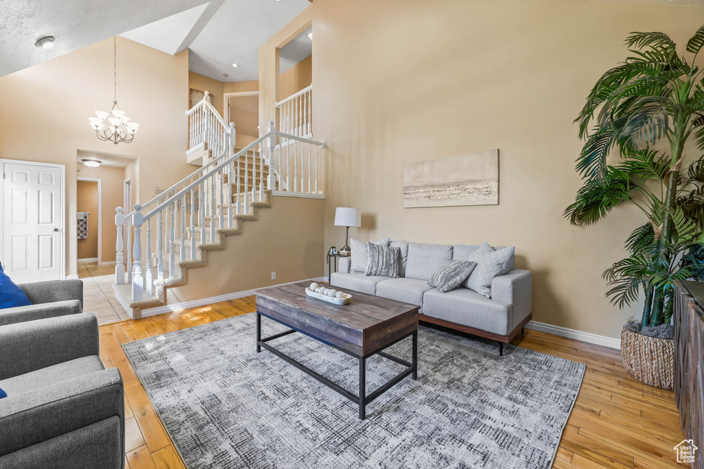 Living area with baseboards, a chandelier, hardwood / wood-style flooring, stairs, and a towering ceiling