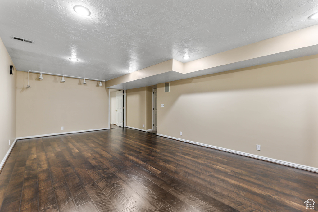 Finished below grade area with wood finished floors, baseboards, and a textured ceiling