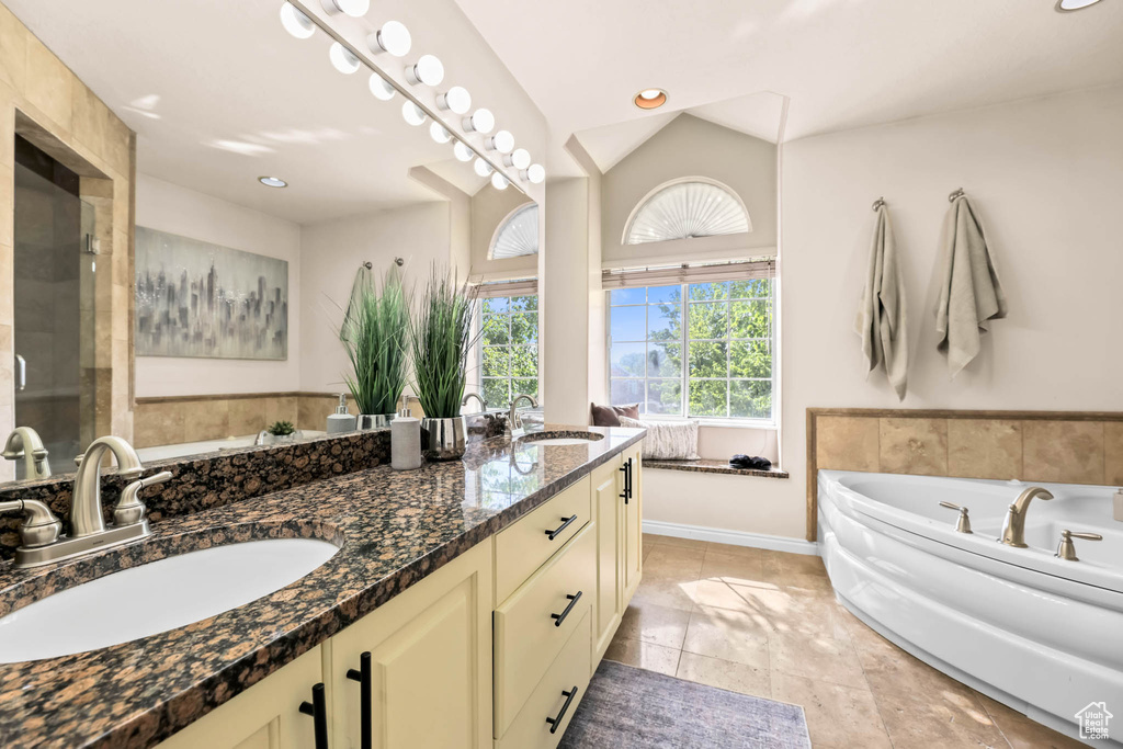 Bathroom with double vanity, a garden tub, baseboards, and recessed lighting