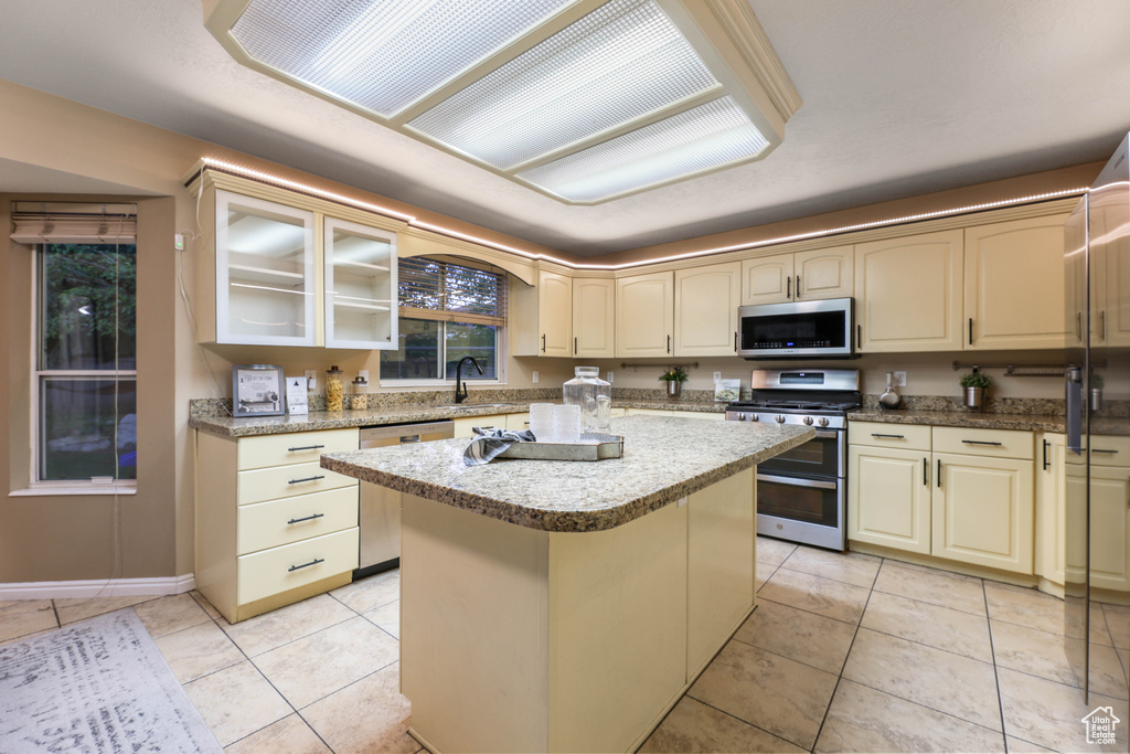 Kitchen with appliances with stainless steel finishes, a kitchen island, cream cabinets, and light tile patterned floors