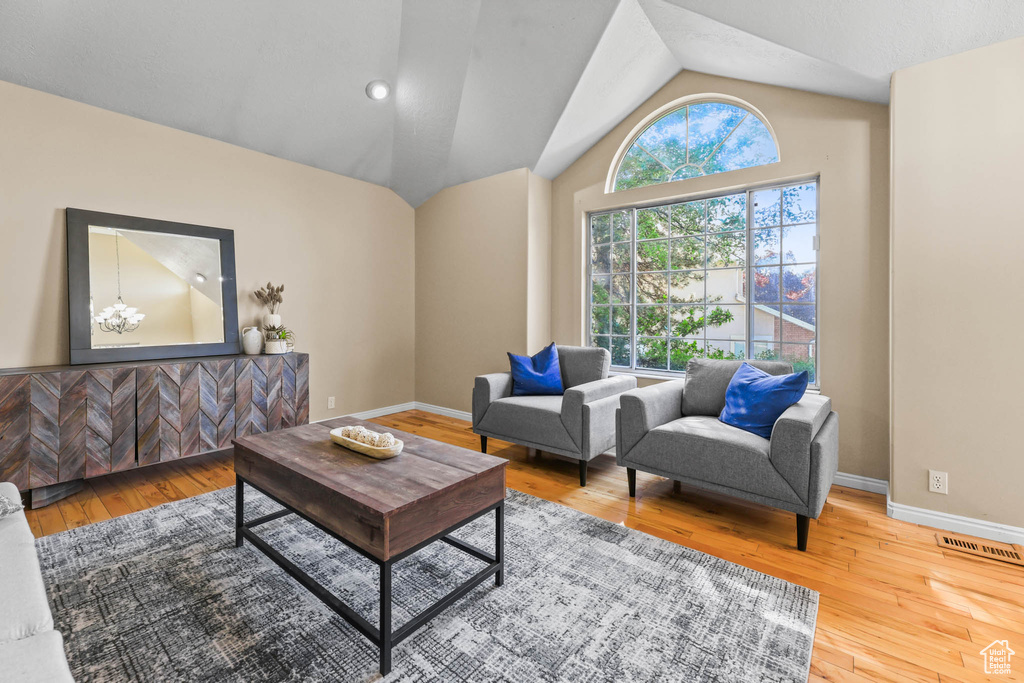 Living room with hardwood / wood-style flooring, vaulted ceiling, and baseboards