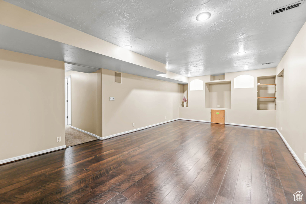 Finished below grade area featuring wood-type flooring, baseboards, and a textured ceiling