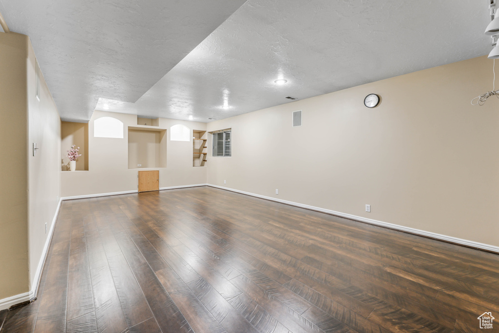 Unfurnished room featuring wood-type flooring, baseboards, and a textured ceiling