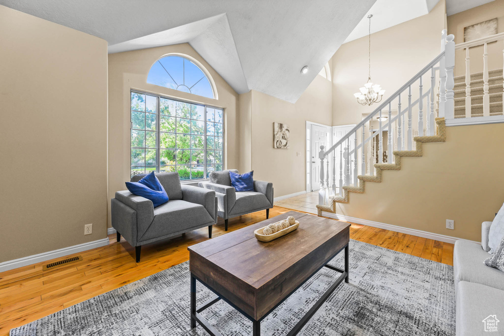 Living room featuring stairway, wood finished floors, baseboards, and vaulted ceiling