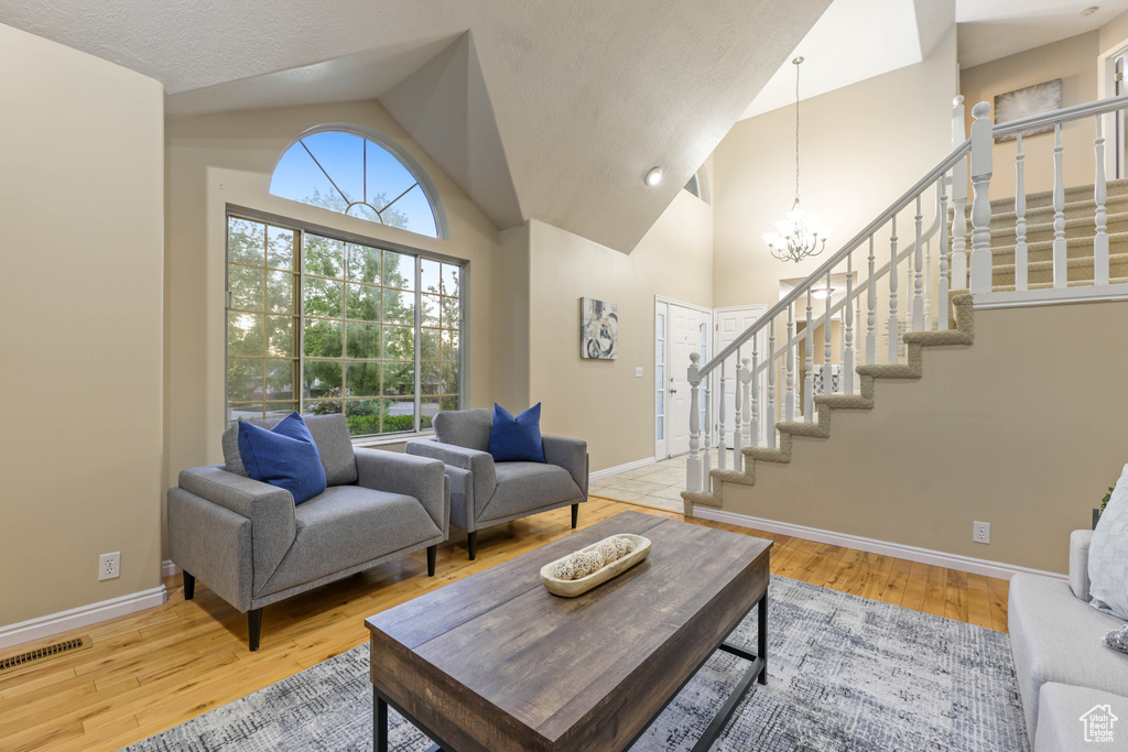 Living area with stairs, a chandelier, baseboards, and lofted ceiling